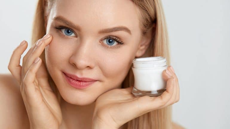 Closeup Of Attractive Young Female Model Putting Cream On Under Eye Skin