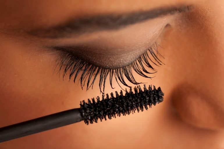 closeup of a woman applying black mascara to her eyelashes