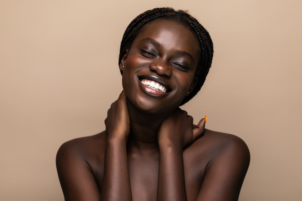 Young adult black woman smiles with eyes closed